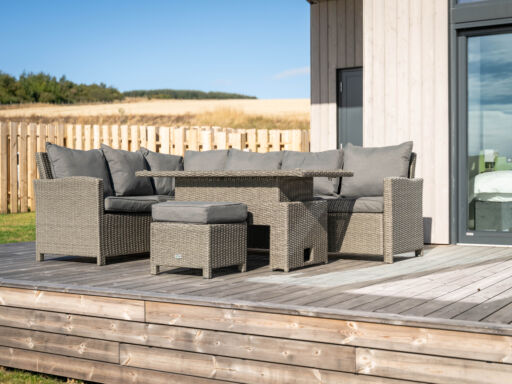 Exterior view of a modern luxury lodge with floor-to-ceiling windows, spacious decking, enclosed garden and private hot tub overlooking Aberdeenshire countryside.
